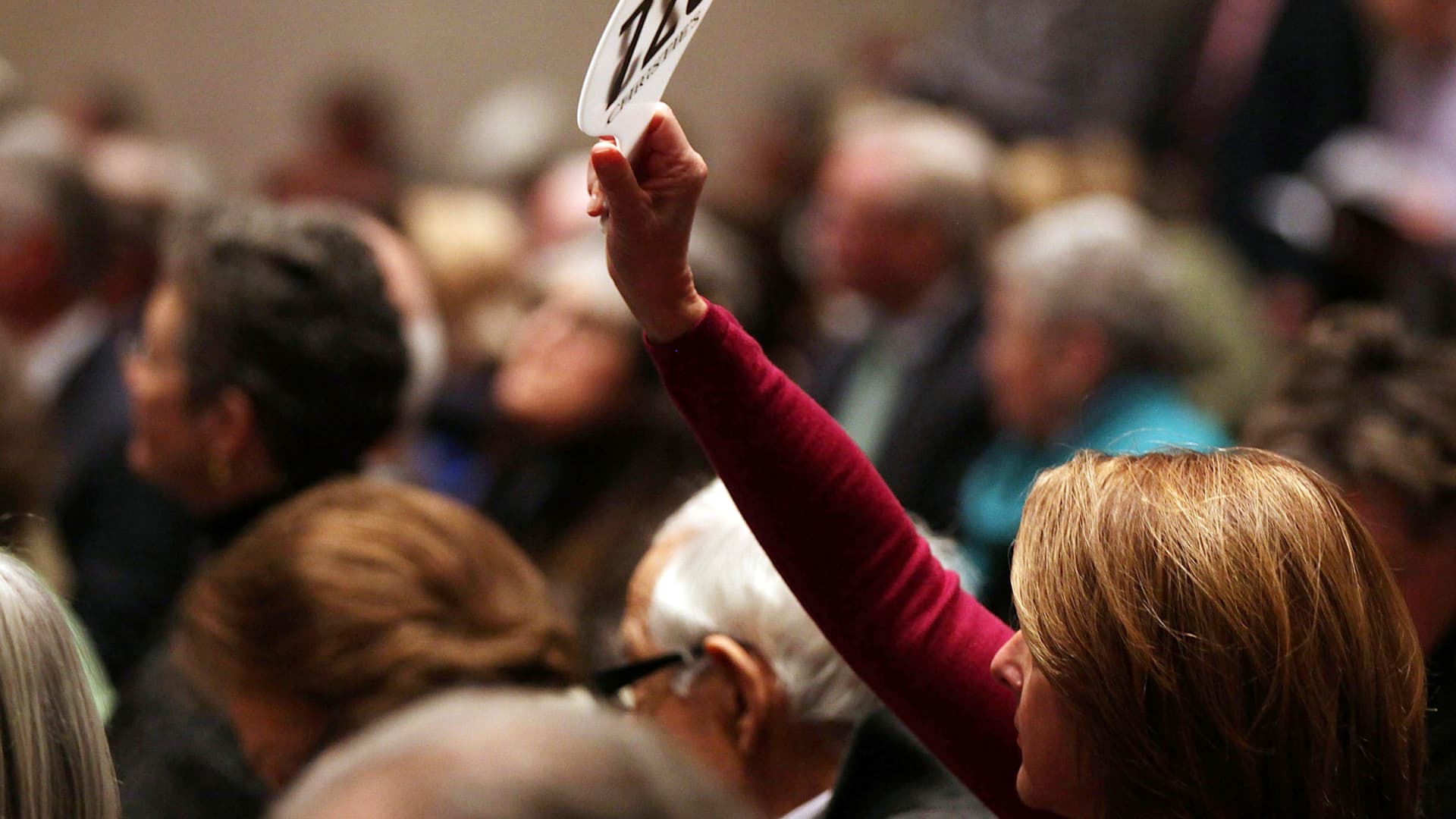 Auction bidder raising a paddle in a crowded room