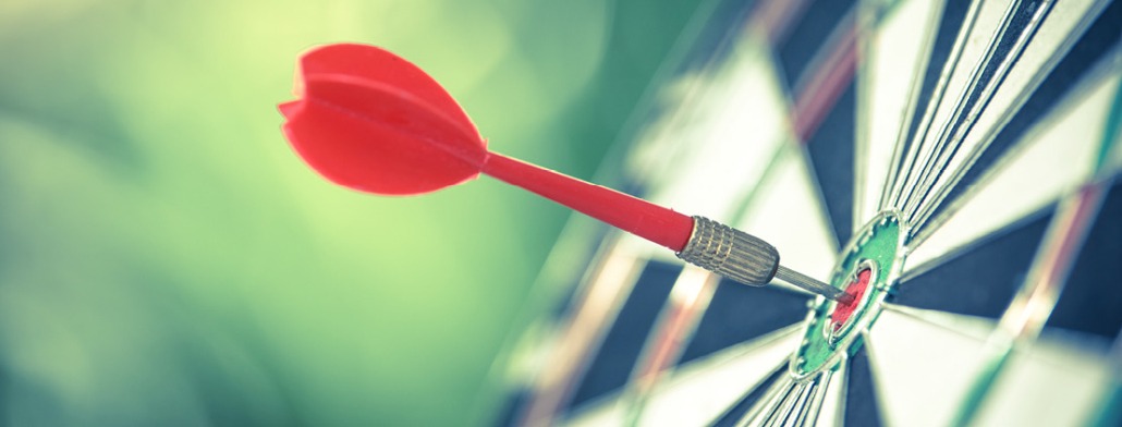 A red dart hitting the bullseye of a dartboard